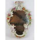 A German porcelain Rococo style mirror decorated with various Putti and roses. Bears the mark of