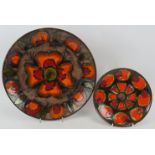 Two 1970s stoneware chargers decorated in orange & red patterns, both signed to reverse. Largest