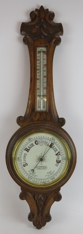 An Edwardian carved oak cased wheel barometer by Aitcheson & Co, London and Leeds. Height 90cm.