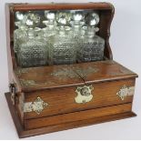 A late 19th century oak tantalus box with three decanters, silver plated mounts, glass