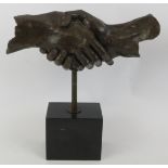 A bronze sculpture of clasped hands mounted on a black marble plinth unsigned. Height 35cm.