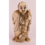 A Japanese Meiji period carved ivory netsuke in the form of a man with a broom, signed to base.