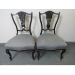 A pair of Edwardian ebonised bedroom chairs, with lyre backs, upholstered in blue pattered material,