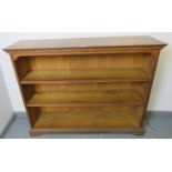 An Edwardian medium oak low open bookcase of two height adjustable shelves, featuring dentil cornice