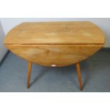 A mid-century Ercol blond elm circular drop-leaf dining table, on canted tapering supports.