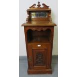 An Edwardian oak bedside cabinet with upper gallery housing a bevelled mirror, and with carved panel