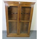 A 19th century oak gun cabinet, with glazed doors opening onto a rack with provision for 6 shotguns.