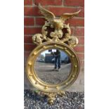 A 19th century style giltwood convex mirror with ornately carved cornice depicting foliate motifs