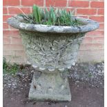 A nicely weathered reconstituted stone garden urn with fruiting vine relief decoration. Condition