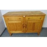 A mid-century Ercol style blond elm and beech sideboard of two short drawers over a double cupboard,