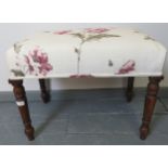 A Victorian mahogany music stool on tapering turned supports, reupholstered in a floral-patterned