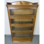 A 1920s medium oak four tier stacking glazed bookcase by Lebus, with ¾ gallery and dentil cornice,