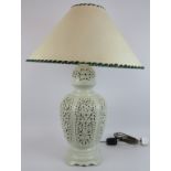 A large reticulated Blanc de Chine lamp of urn form with large green rimmed shade. Lamp base