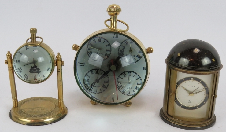 A brass cased orb quartz clock, a similar clock on stand and a German Europa alarm clock in a