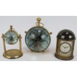 A brass cased orb quartz clock, a similar clock on stand and a German Europa alarm clock in a
