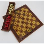 A vintage travelling chess set with folding mahogany board and turned bone chess men. 19cm x 19cm.