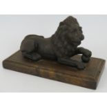 An antique cast iron lion with paw on ball, mounted on oak plinth. Length 23.5cm. Height 14cm.