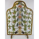 A wrought iron Indian fire screen with cut out animals flowers and foliage decorated in polychrome
