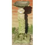 A nicely weathered reconstituted stone birdbath, on a reeded column featuring creeping ivy, and a