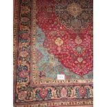 A good Persian Tabriz carpet blue central motif on a deep red ground and turquoise blue spandrels.