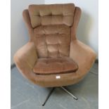 A 1970s wingback ?Blofeld? style swivel chair, upholstered in buttoned brown draylon, on a chrome
