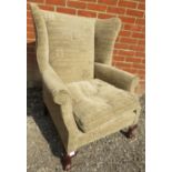 A Georgian style wingback armchair upholstered in a contemporary material featuring Latin text, on