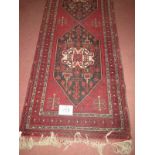 A mid 20th century Persian runner with 3 central repeat pattern on a deep burgundy ground.