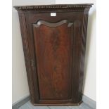 A Georgian mahogany wall hanging corner cupboard with dentil cornice, flanked by reeded columns,
