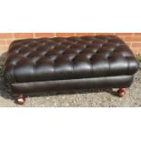 An antique style chesterfield footstool, upholstered in deep buttoned black leather with brass