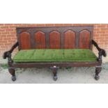 A large Georgian oak settle, with fielded walnut panels to back rest and scrolled armrests, on squat