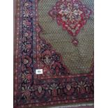 A beautiful Malayer carpet with a central design on red ground, surrounded by a trelice work of blue