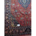 A fine Sarouk carpet with central diamond pattern on a red ground and blue border in very good