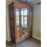 A 19th century style French oak armoire with inset bevelled mirrored panels, scrolled cornice and