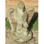 A nicely weathered reconstituted stone garden ornament in the form of an eagle catching aquatic