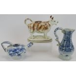 An antique Staffordshire cow creamer, an 18th century blue and white octagonal jug and a similar