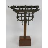 An antique brass/bronze Eastern temple oil lantern on a later wooden display stand. Height:42cm.