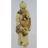 A finely carved Japanese ivory Netsuke, Meiji period of a standing Samurai, decorated in red and