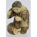 A very finely carved Japanese ivory Netsuke, Meiji period, of a man pulling a creature from a basket