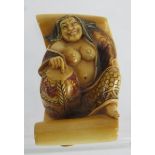 A finely carved Japanese ivory Netsuke, Meiji period, of a semi nude female on a scroll decorated in