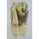 A finely carved Japanese ivory Netsuke, Meiji period, of a traveller with a rat on his back. Height: