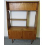 A mid-century teak wall unit with display shelving over a base cupboard, on turned tapering