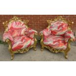 A pair of very ornate giltwood armchairs, the frames carved and pierced in the Rococo style,