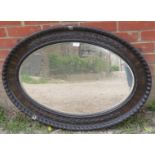 A Victorian bevelled oval wall mirror with mahogany surround featuring gadrooned edging and