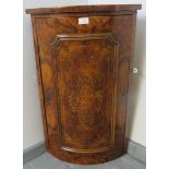 A Victorian burr walnut bow fronted wall hanging corner cupboard featuring marquetry inlay, with