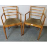 A pair of Art Deco light oak open sided elbow chairs, with drop-in seat pads, on tapering square