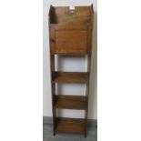An Arts & Crafts elm and oak narrow open bookcase of three shelves, with locking cupboard and