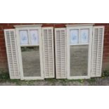 A pair of white painted rectangular wall mirrors with louvered shutters and inset floral panels in