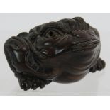 A finely carved Japanese hardwood Netsuke of a frog with his tongue out. Height: 2.5cm. Signed panel