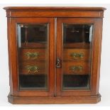 An Edwardian glazed oak smoker's cabinet internally fitted with four drawers, two pipe racks and a