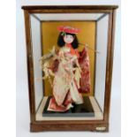 A fashion model of a Japanese Geisha in silk robes displayed in a glazed wooden case. Overall